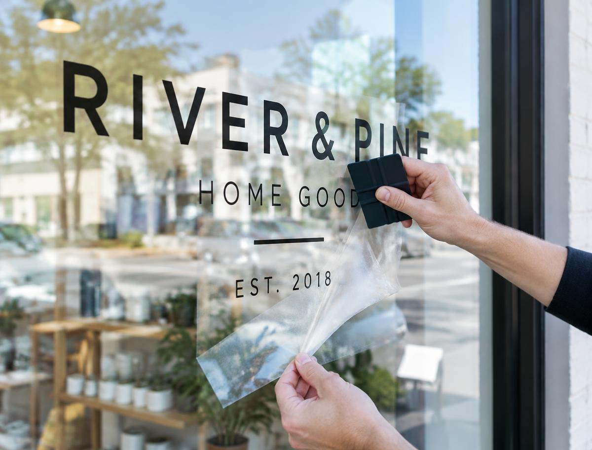 Cut vinyl lettering being squeegeed onto a shop window